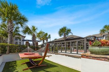 a hammock on the balcony of a house with palm trees at The Loree, Jacksonville, 32256